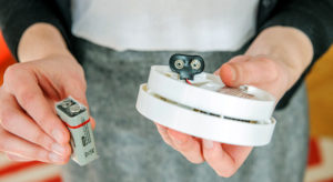 Person replacing smoke alarm battery