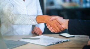 Two people shaking hands after signing a contract