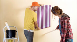 A man and a woman safely installing wallpaper
